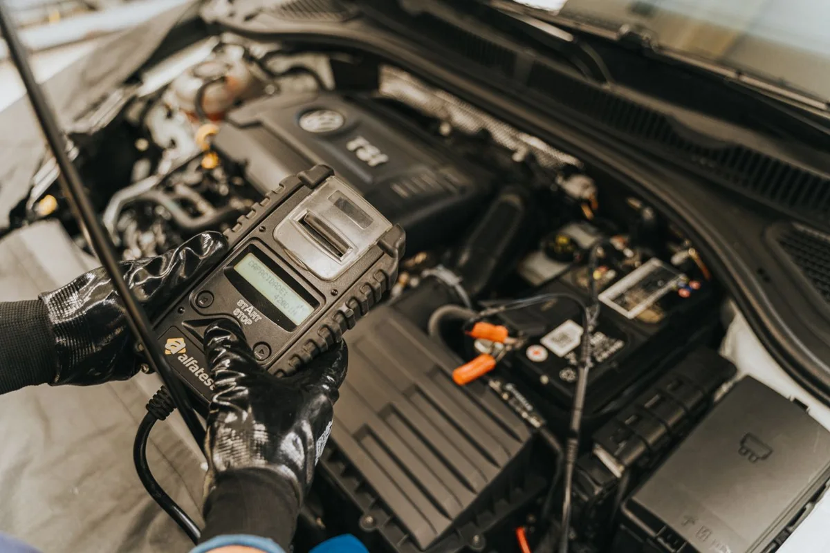 Un appareil de diagnostic tenu près du compartiment moteur d’une voiture à l’arrêt