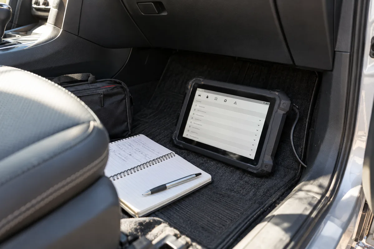 Diagnostic tablet and notebook in a parked car footwell