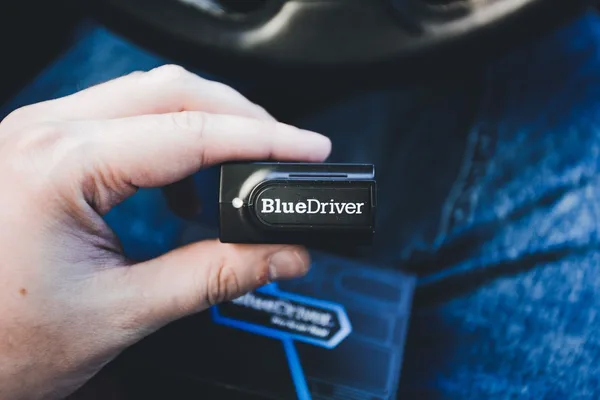 Lecteur OBD portable tenu dans l'habitacle d'une voiture à l'arrêt