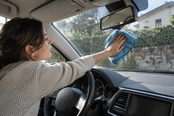 Un chiffon nettoyant l’intérieur du pare-brise d’une voiture arrêtée