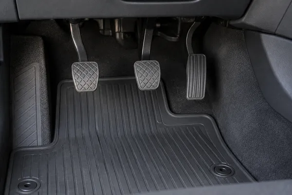 Trois pédales et un tapis fixé dans une voiture manuelle