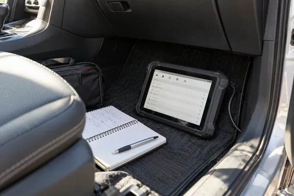 Tablette de diagnostic et carnet dans le plancher d'une voiture arrêtée