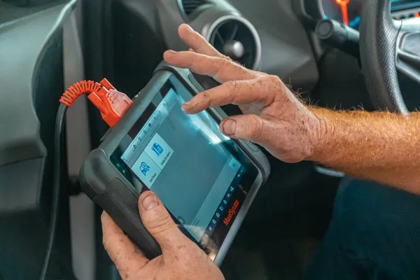 Un technicien utilise une tablette de diagnostic dans une voiture à l’arrêt