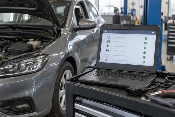 Ordinateur de diagnostic sur un chariot près d’un compartiment moteur ouvert
