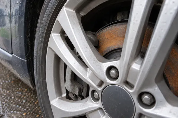 Un léger voile de rouille visible sur le disque d’une voiture garée.